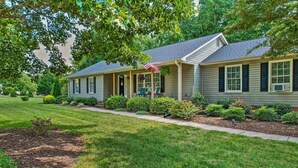 A two-story house with a covered porch, a small garden, and a well-maintained lawn. - Peaceful Country Retreat w/ Easy Highway Access! (Browns Summit)