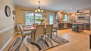 A modern kitchen with a dining area, featuring a chandelier, wooden chairs, and a large island with stools. - Peaceful Country Retreat w/ Easy Highway Access! (Browns Summit)
