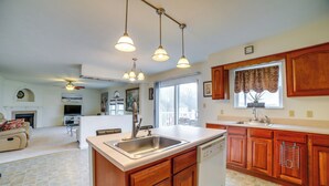 A spacious kitchen with wooden cabinets, a large island with a sink, and pendant lighting. - Pet-friendly Apollo Home w/ Furnished Deck! (Apollo)