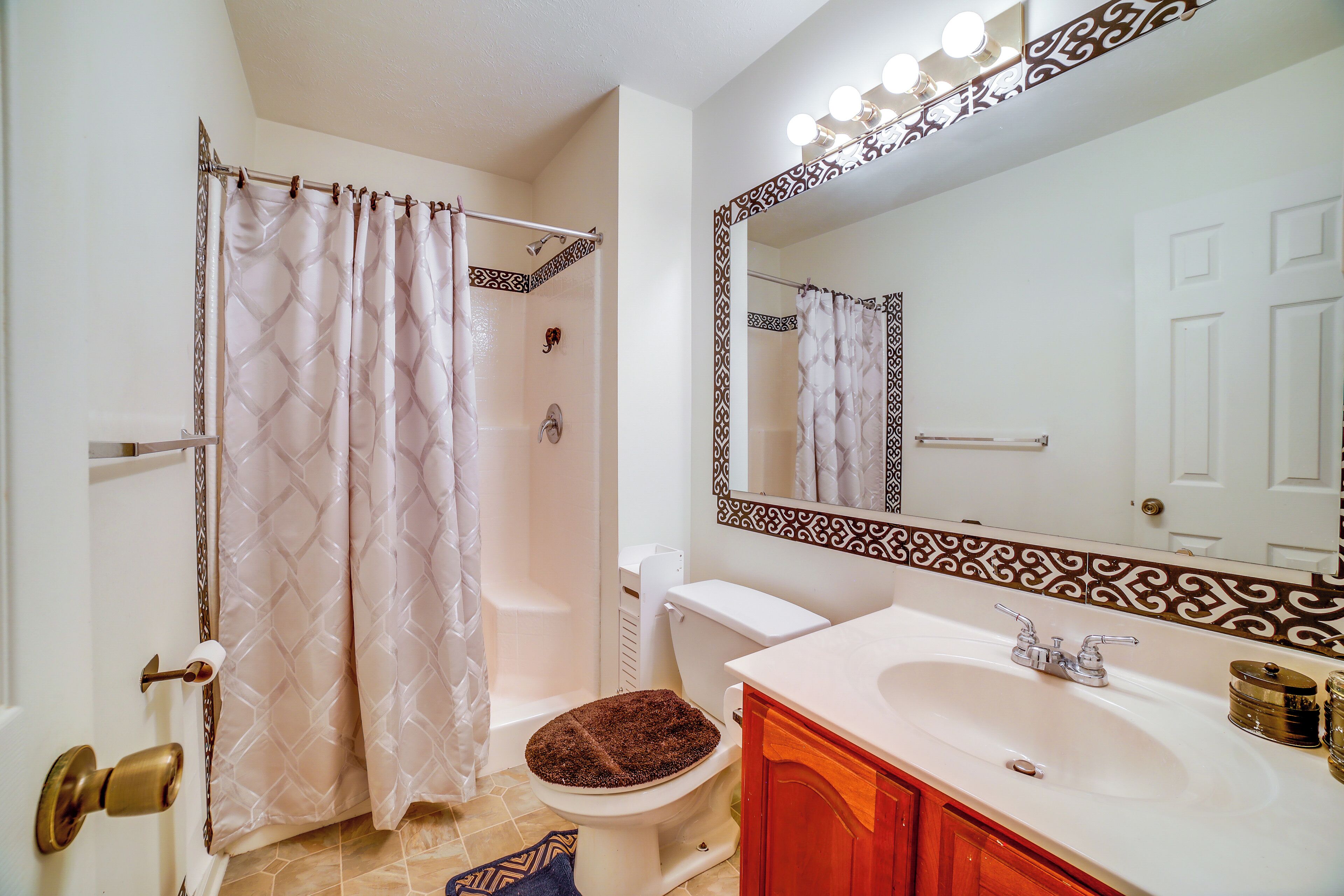 A bathroom with a shower curtain, toilet, sink, and mirror.