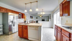 A kitchen with wooden cabinets, a stainless steel refrigerator, a dishwasher, and pendant lights. - Pet-friendly Apollo Home w/ Furnished Deck! (Apollo)