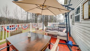 Une terrasse extérieure couverte, équipée d’une table et de chaises, d’un canapé et d’un parasol.