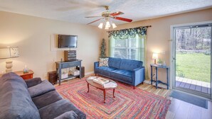 A living room with a blue sofa, a coffee table, a TV, and a ceiling fan. - Tracy City Home Near South Cumberland State Park! (Tracy City)