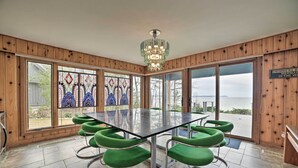 A dining area with a large table and green chairs, large windows with stained glass, and a wooden interior. - Lk Michigan Escape: Sunsets, Fireplace, Wine Trail (Lake Leelanau)