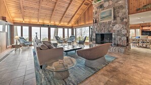 A spacious living area with a stone fireplace, comfortable seating, and large windows overlooking Lake Michigan. - Lk Michigan Escape: Sunsets, Fireplace, Wine Trail (Lake Leelanau)