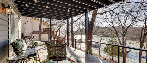A covered porch with outdoor seating, a view of a river, and a wooden deck.