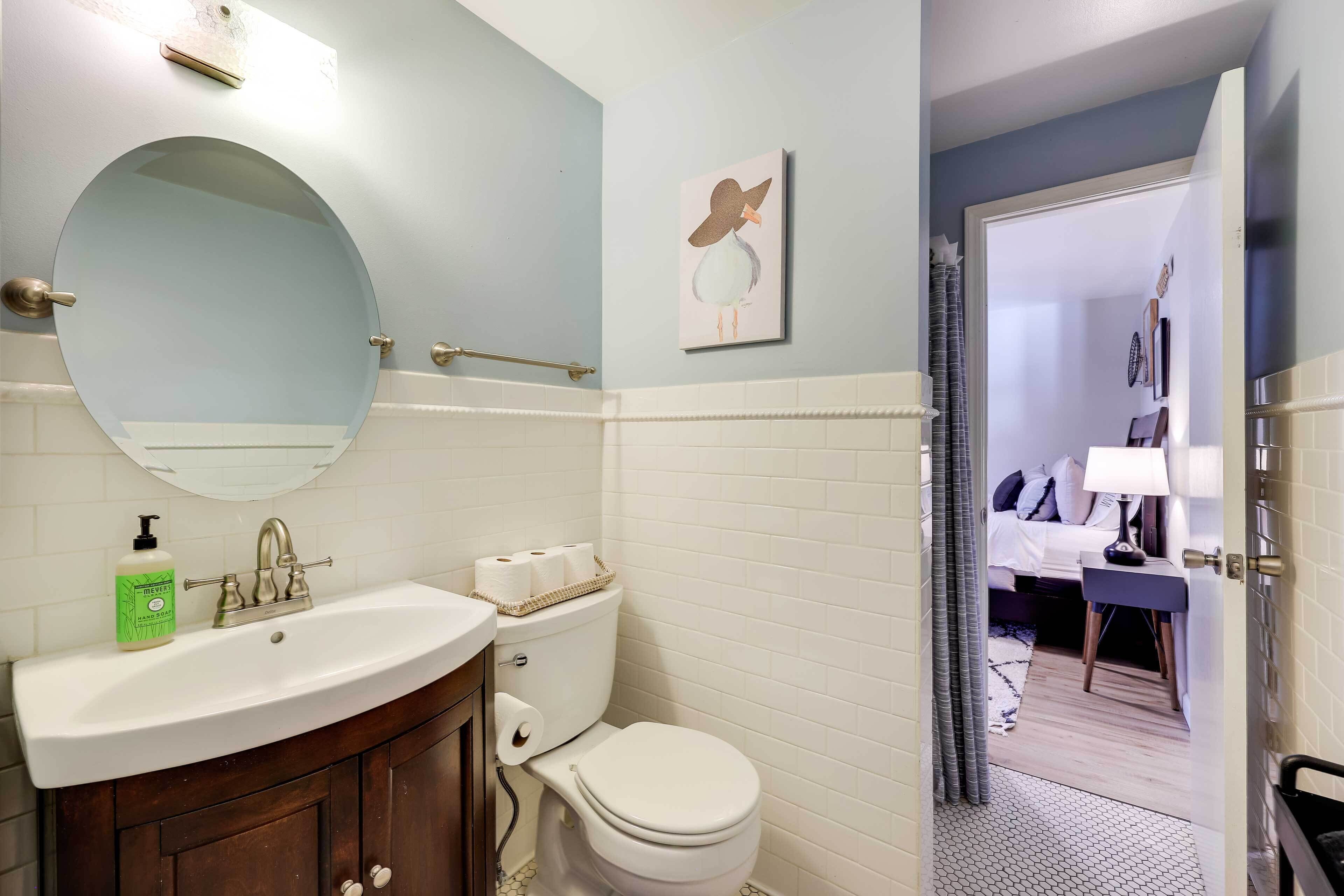 Une salle de bain avec un miroir rond, un lavabo, des toilettes et un espace douche.