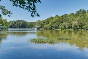 A serene lake with a dock and a covered area, surrounded by dense forest.