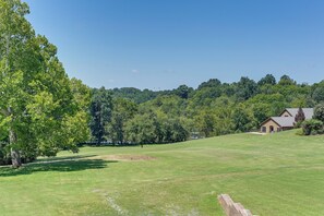 A grassy field with a house and trees in the background.