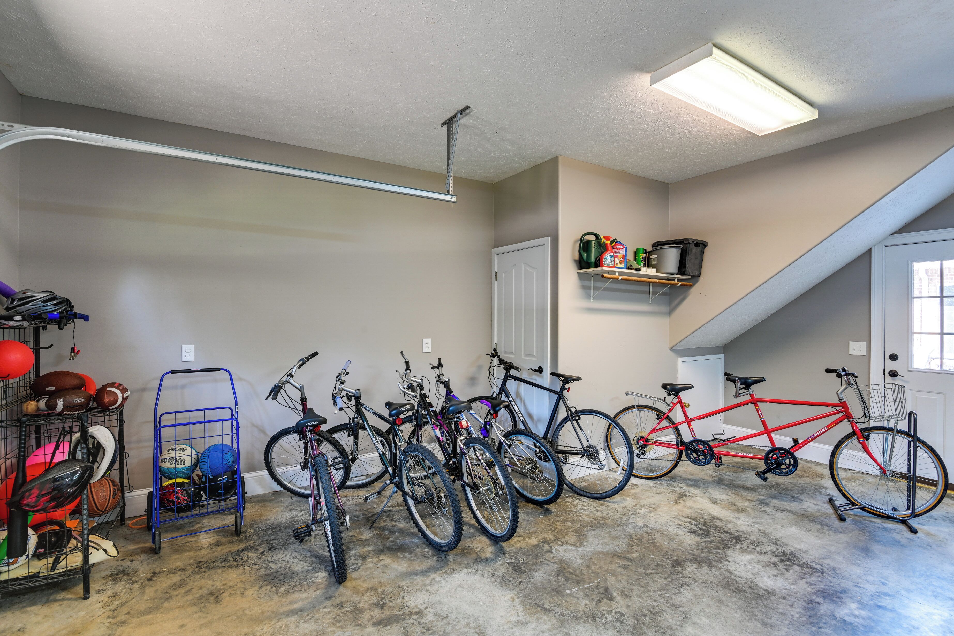A garage with bicycles, sports equipment, and a ceiling light fixture.