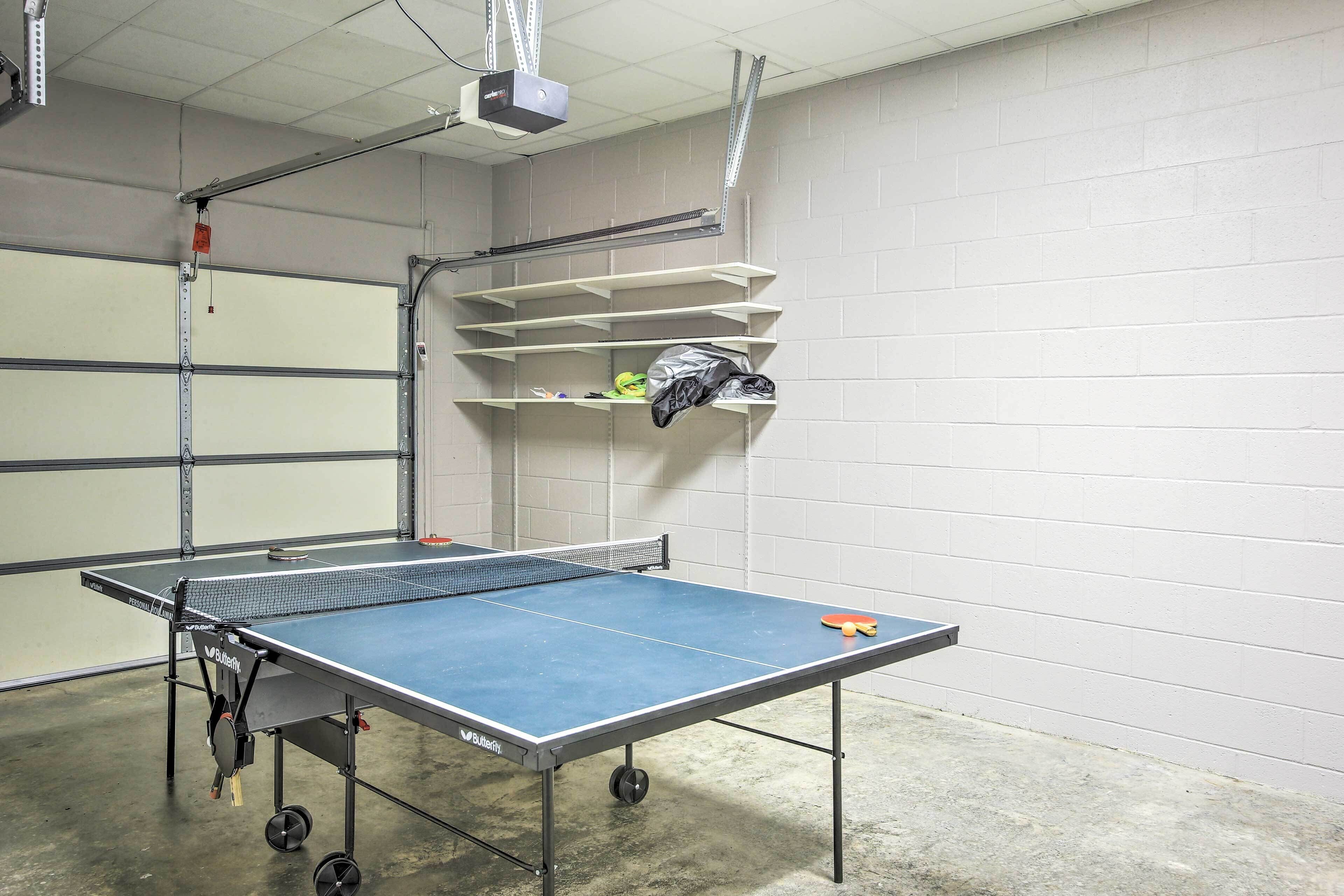 A ping pong table in a room with white brick walls, a ceiling-mounted projector, and metal shelving units.