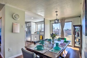 Comedor con vajilla color turquesa, una cocina al fondo y un calendario en la pared.