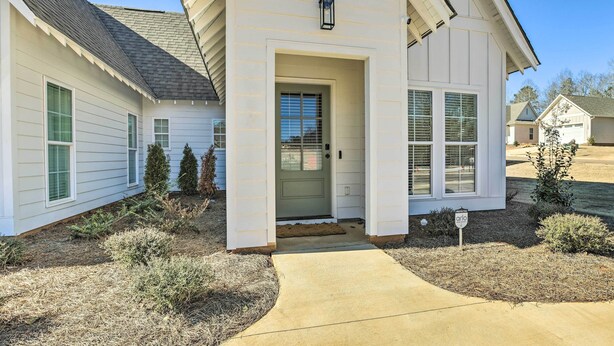 A single-story house with a front porch, a mailbox, and a small garden with shrubs and a tree. - Opelika Townhome w/ Central A/C + Heating! (Opelika)