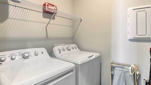 A laundry area with two washing machines, a drying rack, and a wall-mounted heater. - Opelika Townhome w/ Central A/C + Heating! (Opelika)