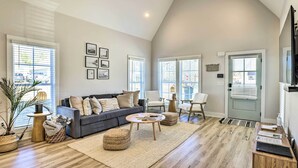 A spacious living room with a grey sofa, ottomans, a coffee table, and a TV. - Opelika Townhome w/ Central A/C + Heating! (Opelika)