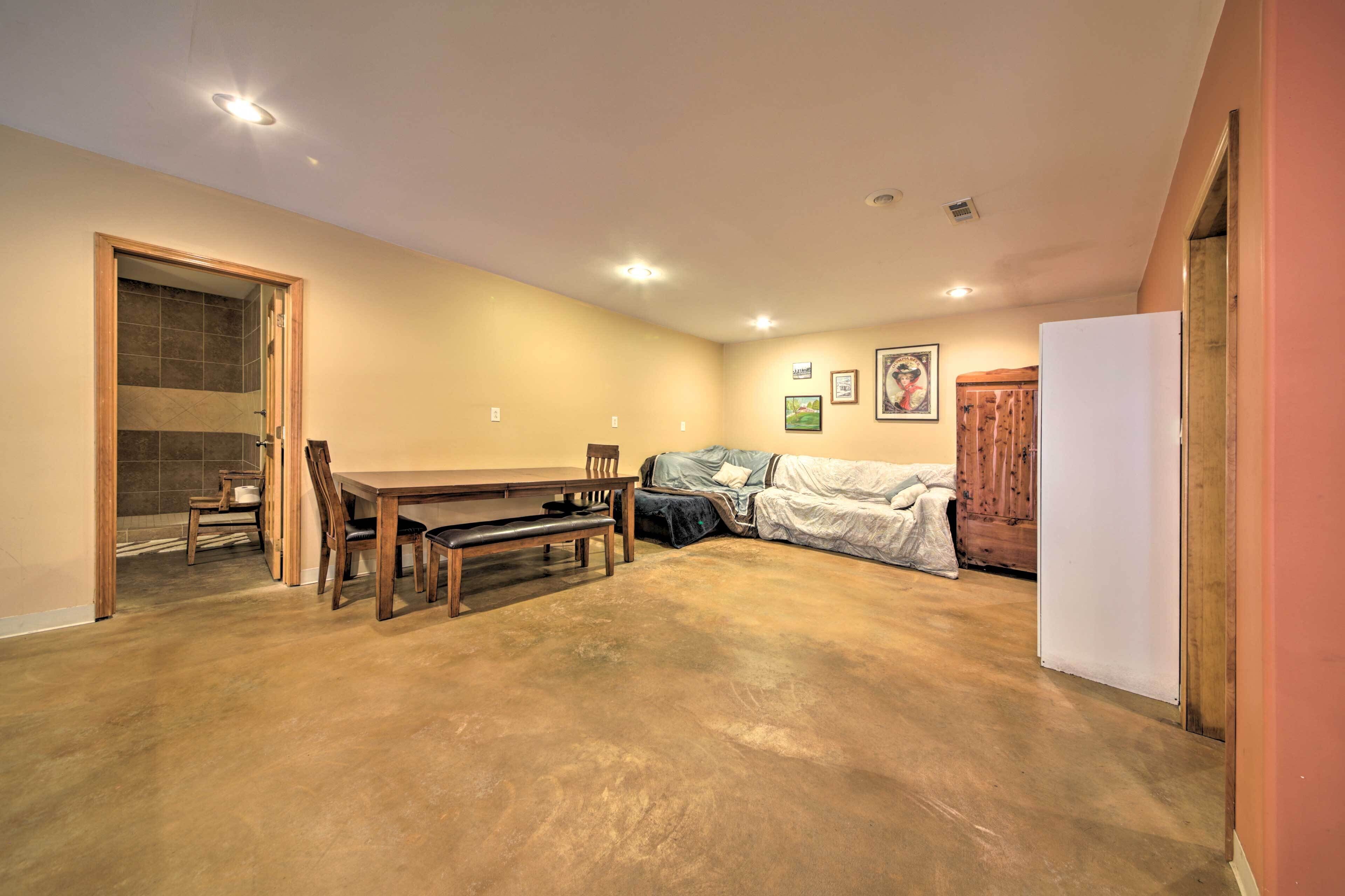 A spacious living room with a wooden dining table, chairs, a sofa, and a cabinet.