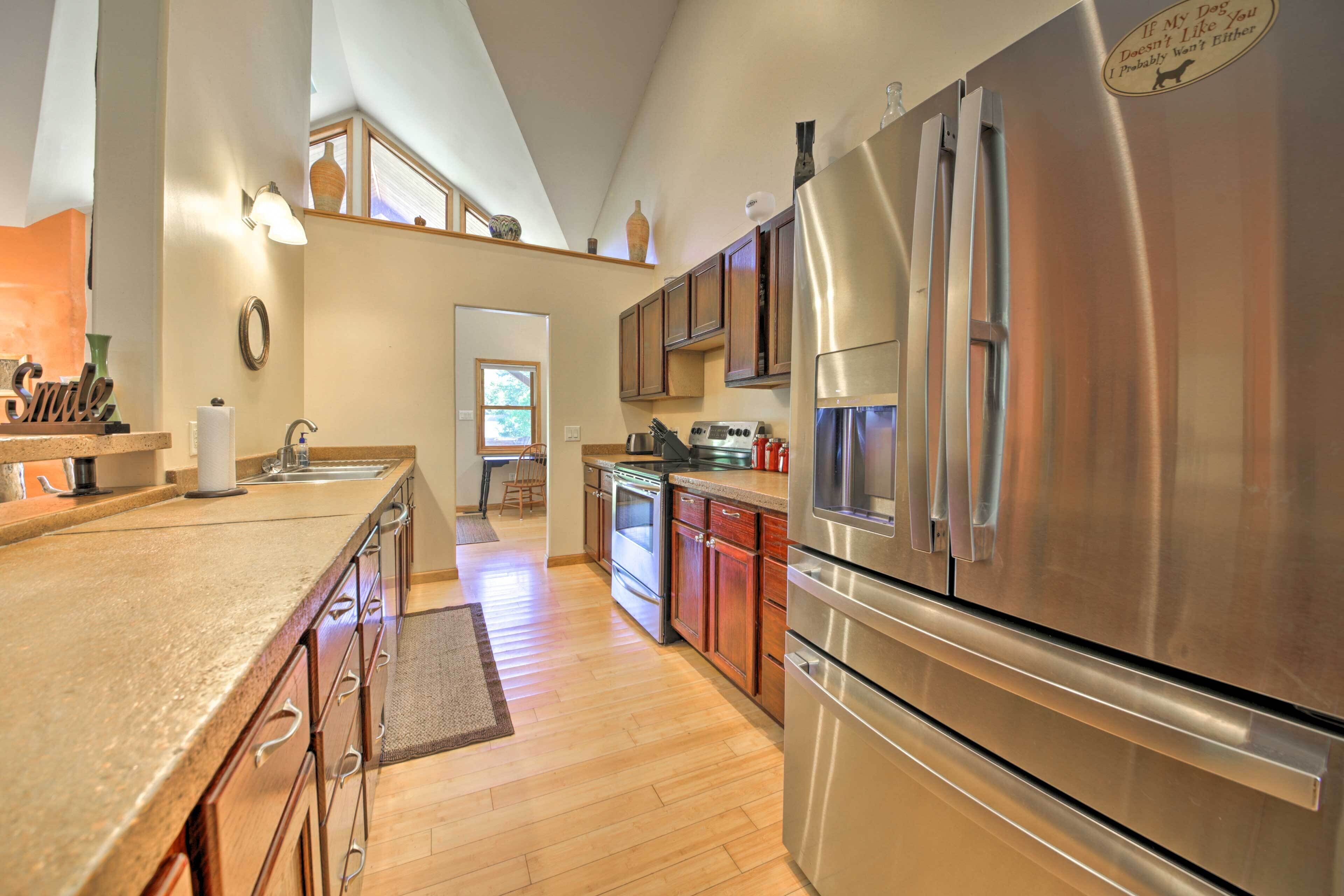 A modern kitchen with stainless steel appliances, wooden cabinets, and a large island.