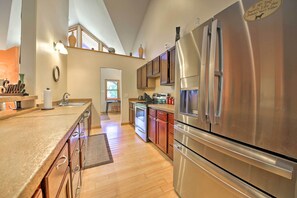 A modern kitchen with stainless steel appliances, wooden cabinets, and a large island.