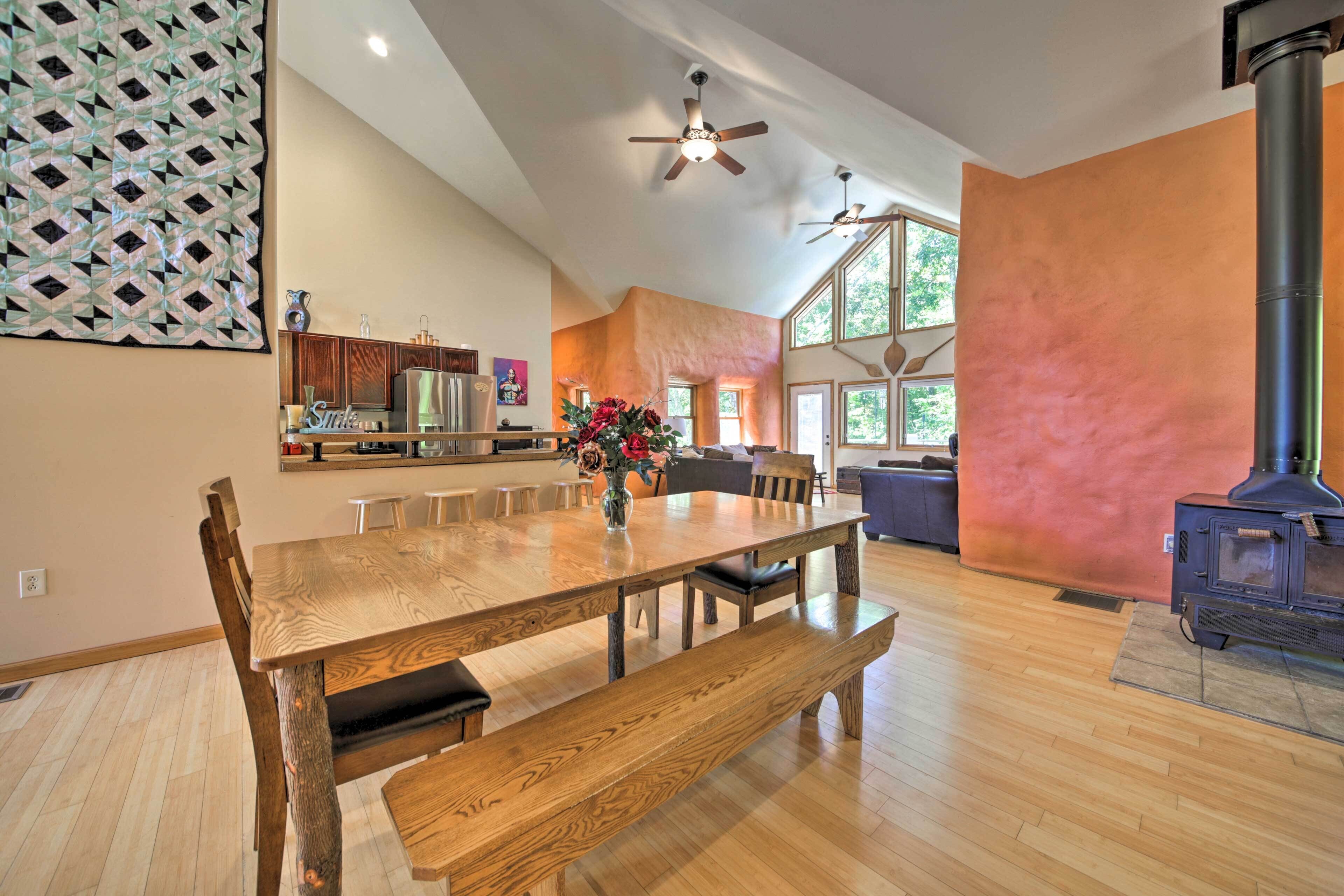 A spacious living area with a wooden dining table, benches, and a large window.