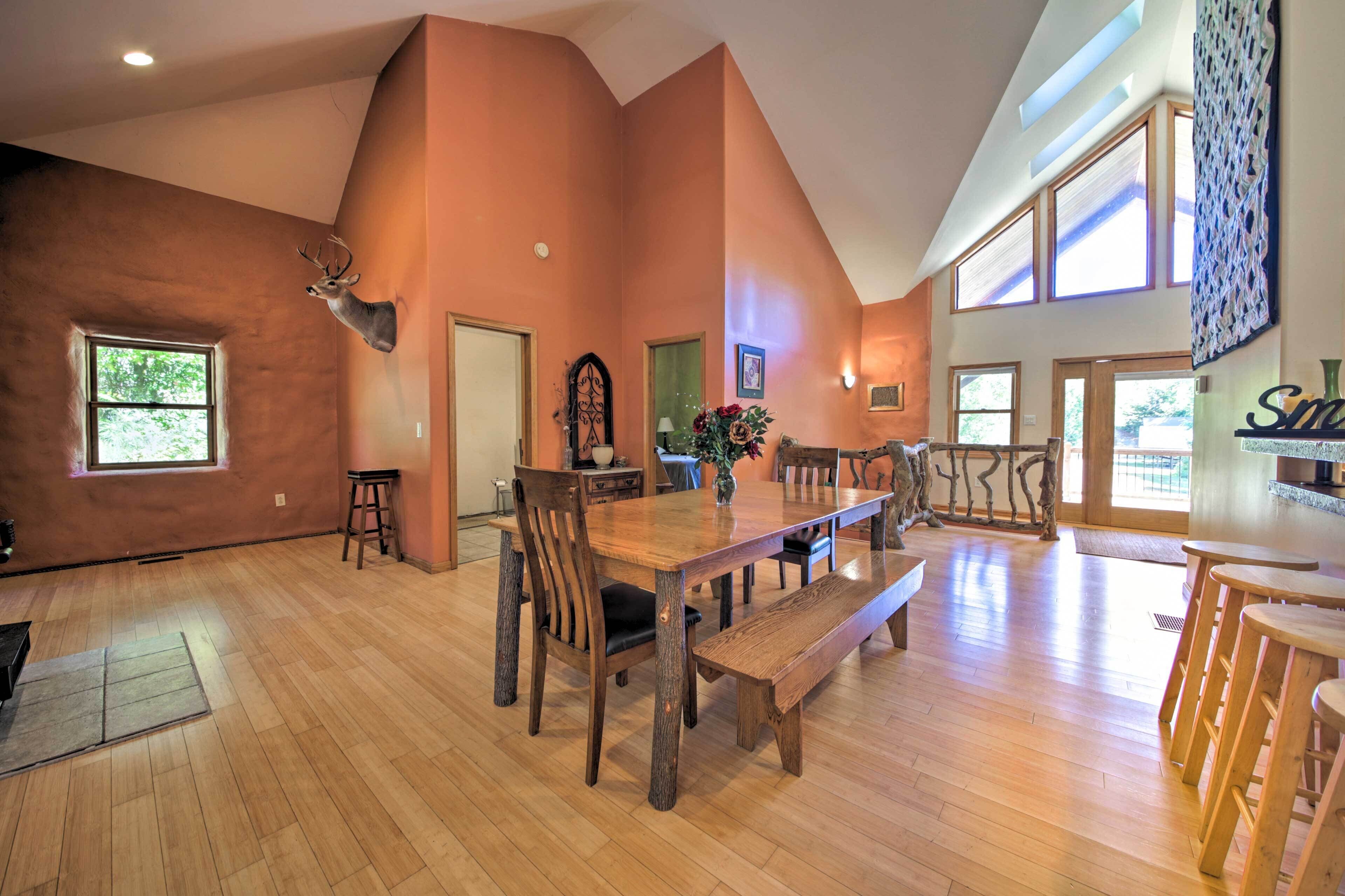 Een ruime eethoek met een grote houten tafel, banken en een opgehangen hertenkop aan de muur.