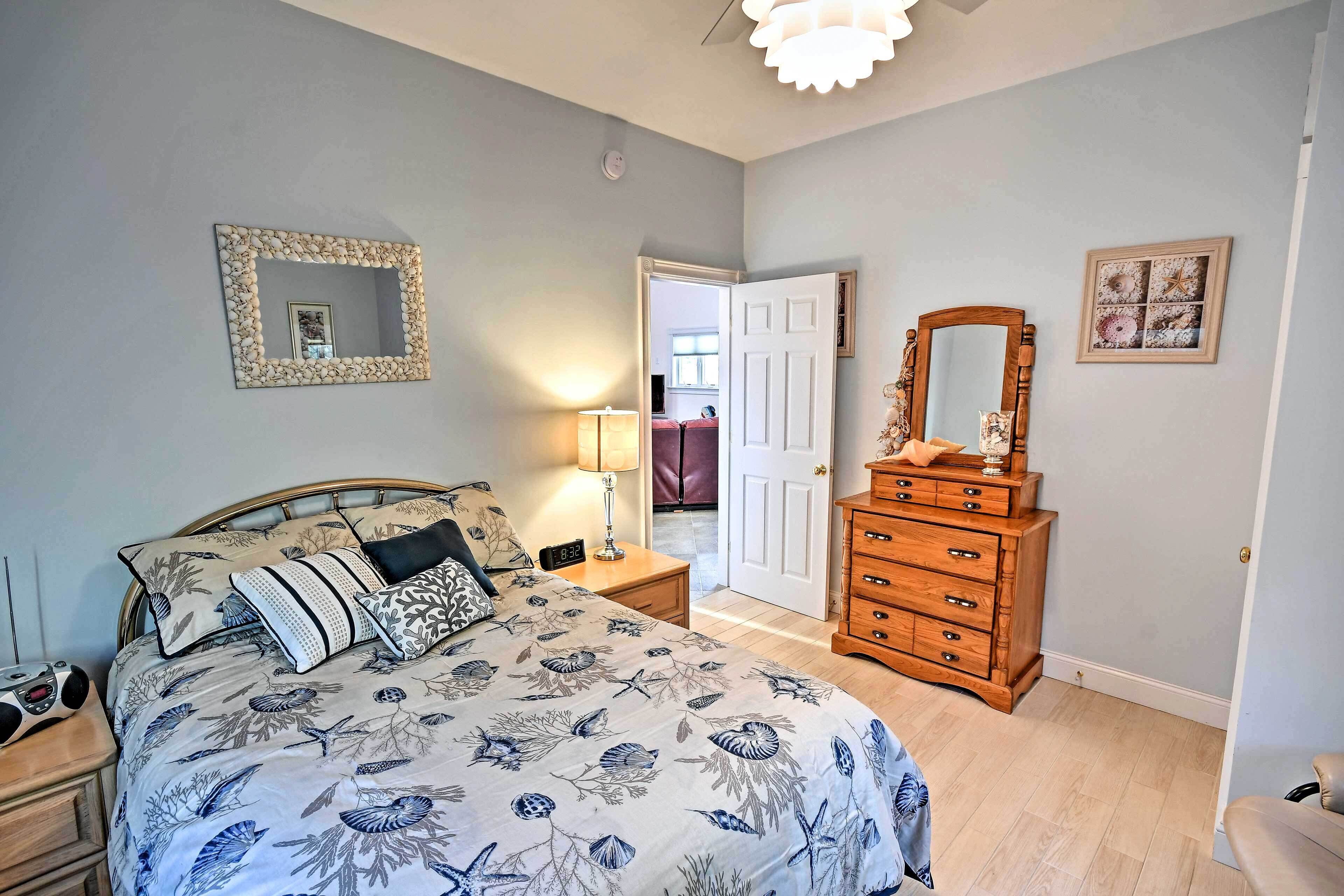 Un dormitorio con cama, cómoda y dos espejos en la pared.