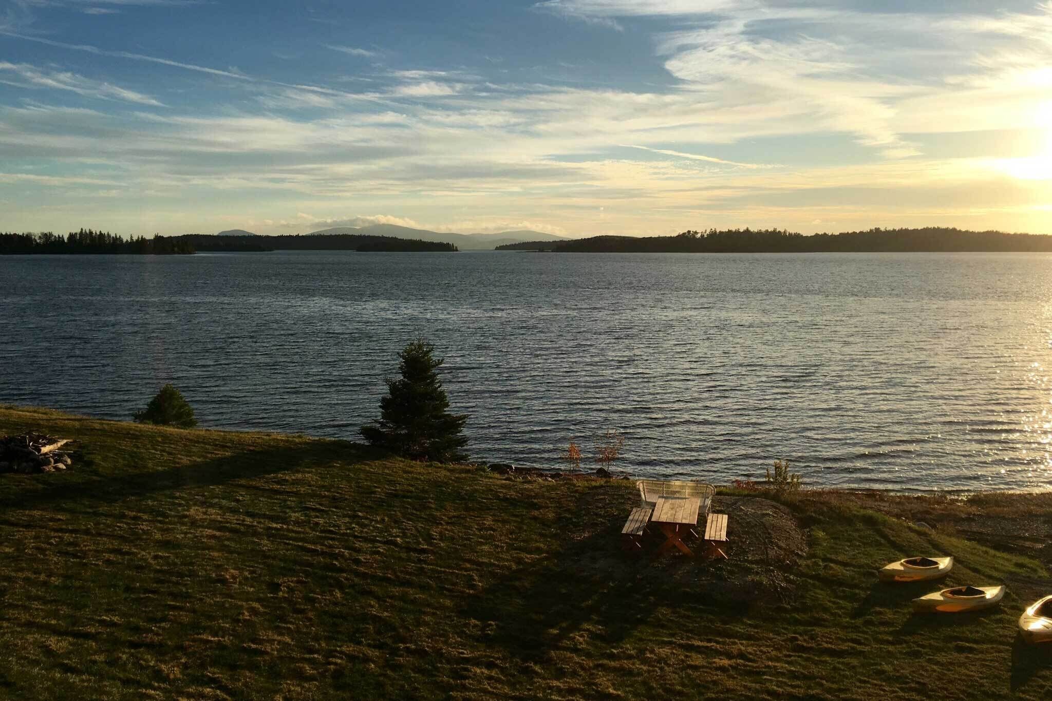 A lakeside view with a wooden bench and canoes.