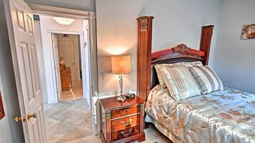 Un dormitorio con cama, mesita de noche, lámpara y una puerta que da a otra habitación.
