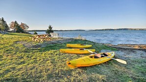 A lakeside picnic area with kayaks and a table. - 2BR Coastal Gem! Breathtaking Ocean/mountain View (Sullivan)