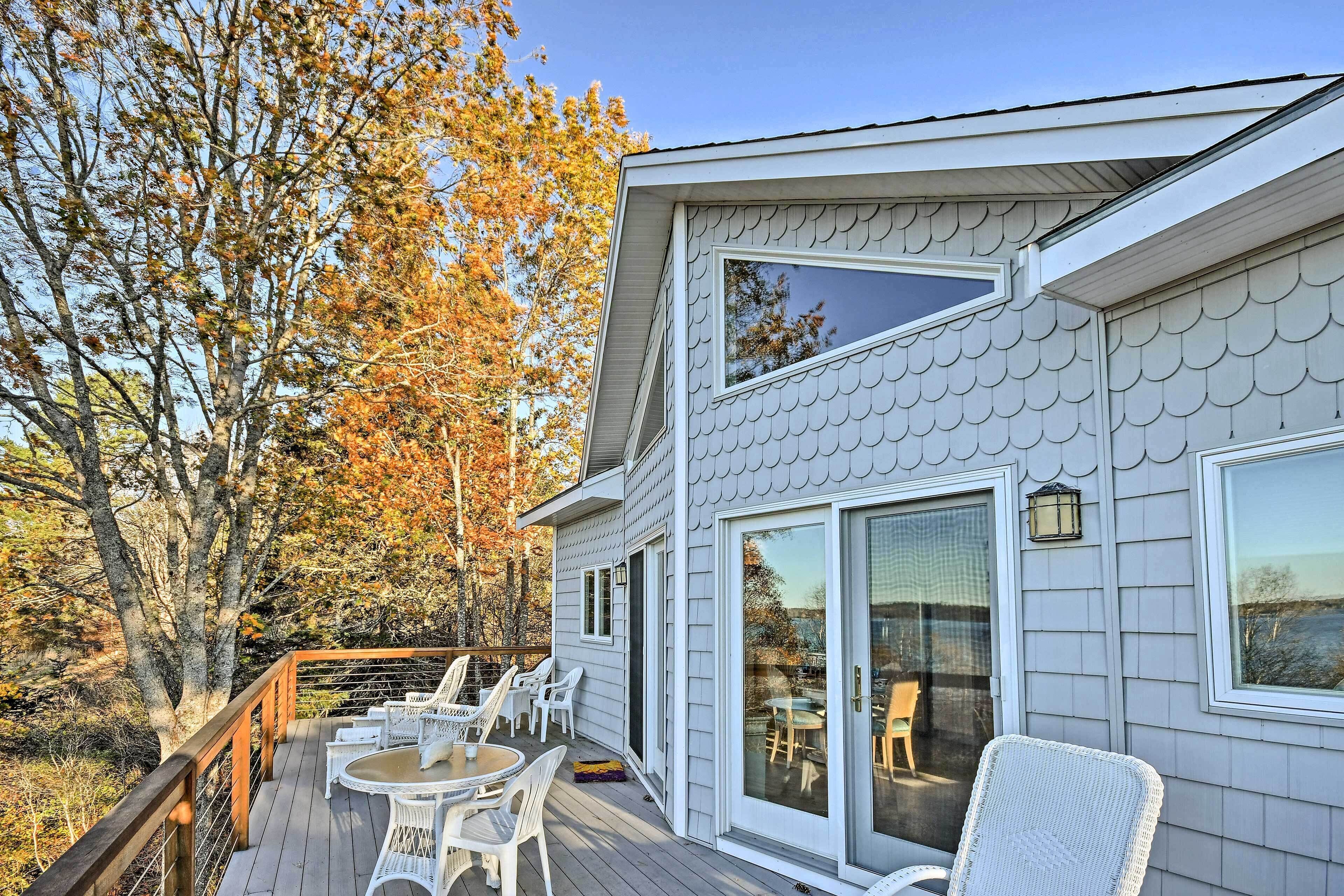 A house with a deck, white exterior, and large windows.