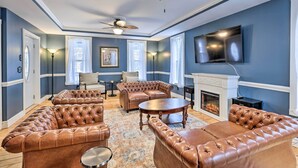 A living room with leather sofas, a fireplace, and a television mounted on the wall. - Walkable Sodus Point Retreat < 1 Mi to Lake (Sodus Point)