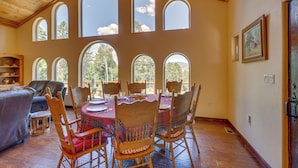 Comedor con una mesa de madera dispuesta para seis personas, rodeada de sillas de madera con cojines a cuadros.