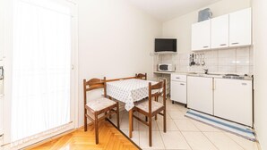 Une cuisine de taille réduite, avec des meubles blancs, un four à micro-ondes et un petit réfrigérateur.