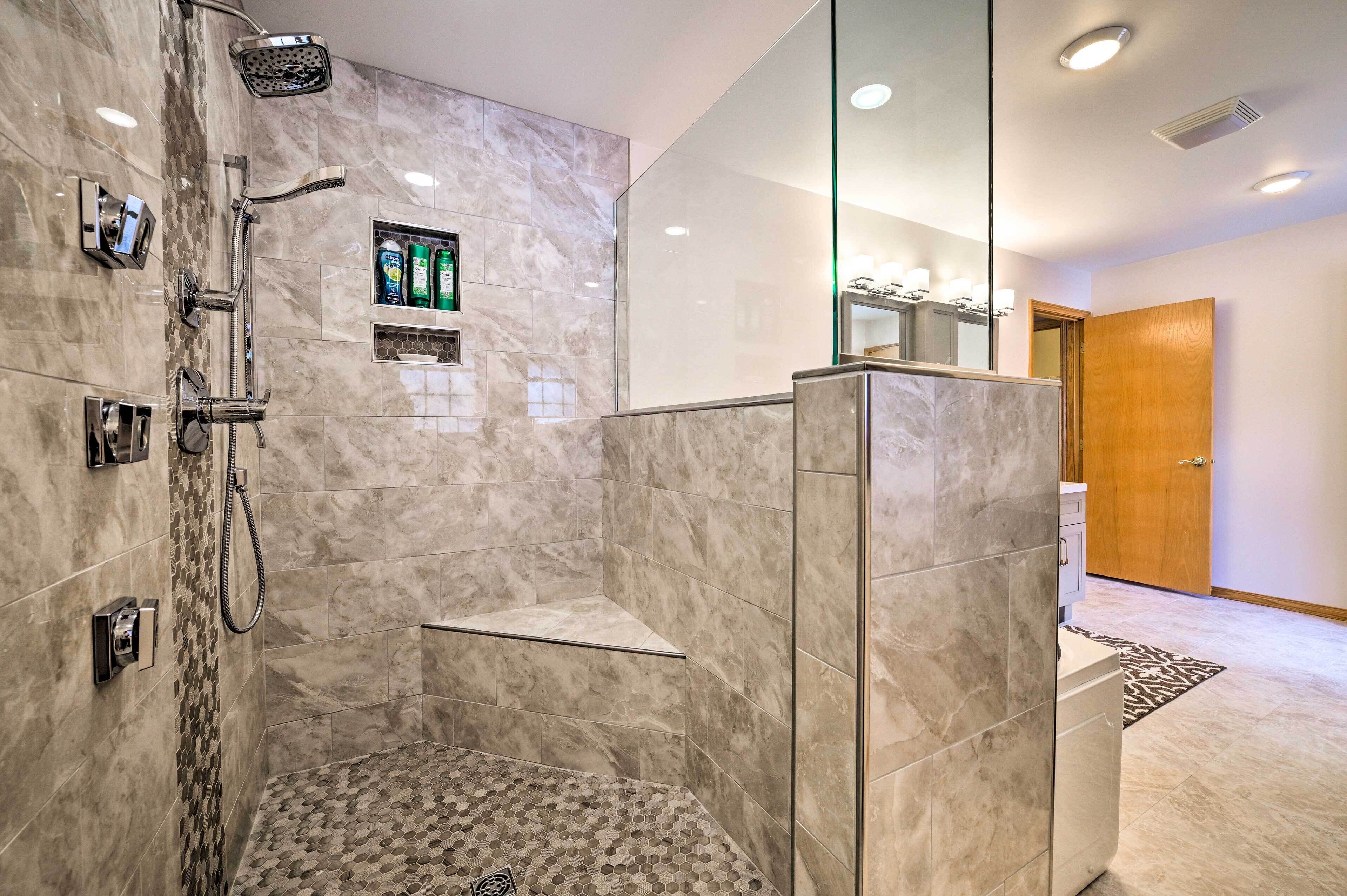 A modern bathroom with a shower, a glass-enclosed vanity, and a wooden door.