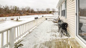 A covered outdoor area with a wooden deck, white railing, and outdoor furniture. - Waterfront Evart House on Chippewa Lake Channel (Evart)