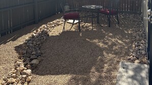 A backyard with a wooden fence, a patio table with chairs, and a large umbrella. - Cozy Retro Downtown Living (Albuquerque)