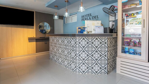 Un espace d’accueil d’hôtel avec un comptoir décoré, un téléviseur fixé au mur et un mini-bar.