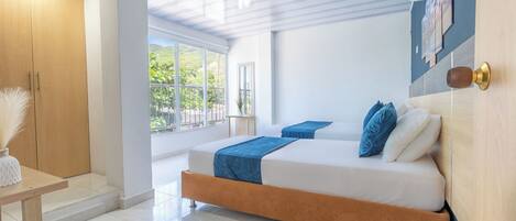 A modern bedroom with a large bed, wooden wardrobe, and a view of greenery outside.