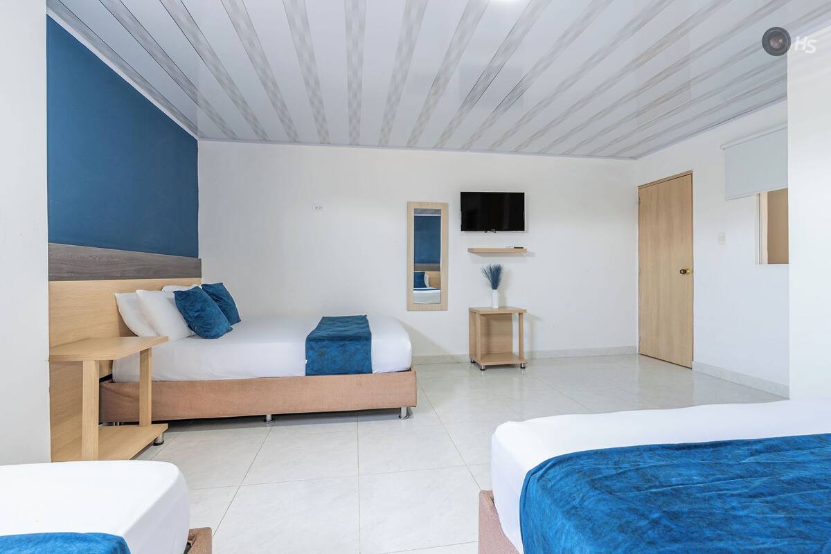 Une chambre à coucher moderne avec un lit, des tables de chevet, une télévision et un miroir.