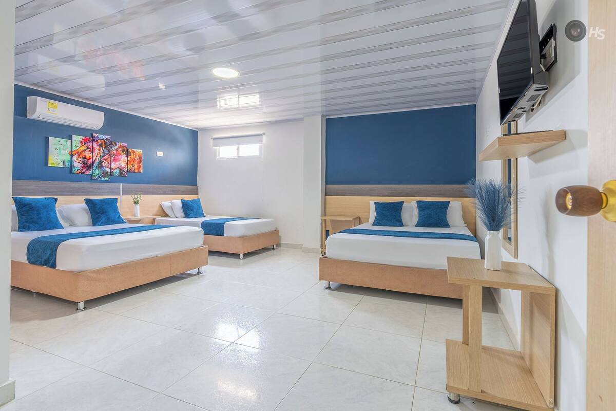 Une chambre d’hôtel avec deux lits, un téléviseur, un climatiseur fixé au mur et une fenêtre.
