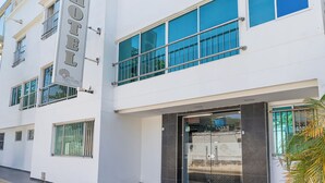 A modern hotel with a prominent sign, large windows, and a glass entrance. - Hotel Perla Del Caribe (Santa Marta)