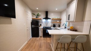 Una cocina compacta con una isla central, un refrigerador negro, una estufa y un lavaplatos.