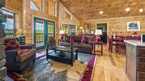 Un interior de cabaña de madera espacioso, con una amplia sala de estar, una mesa de comedor y una zona de cocina.