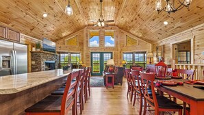 Una cocina amplia con una isla grande, techo de madera y chimenea de piedra.