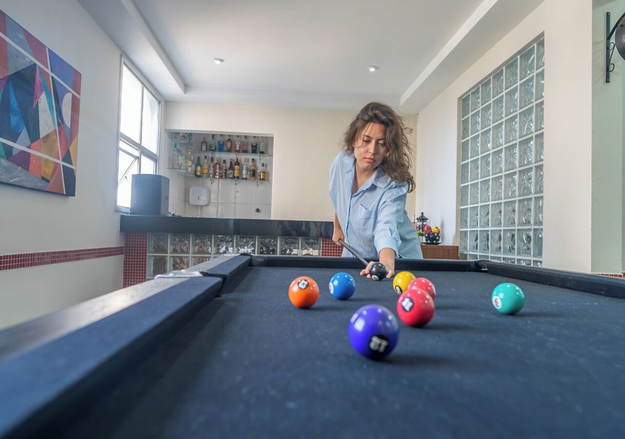 A pool table in a room with a tiled backsplash and a window.