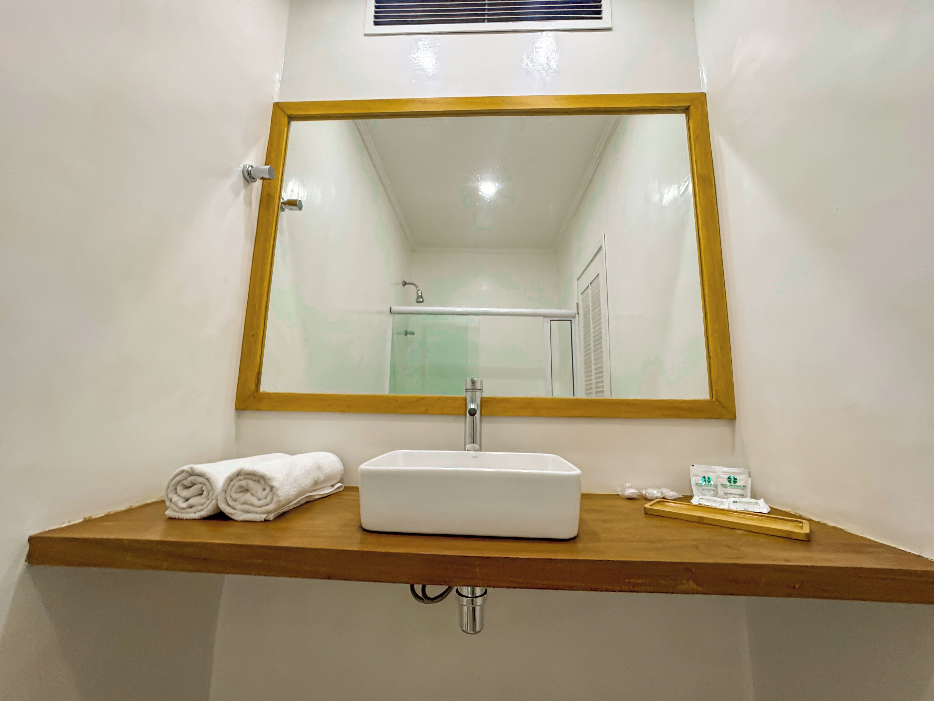 A bathroom with a wooden vanity, a white sink, a mirror with a wooden frame, and a towel on the counter.