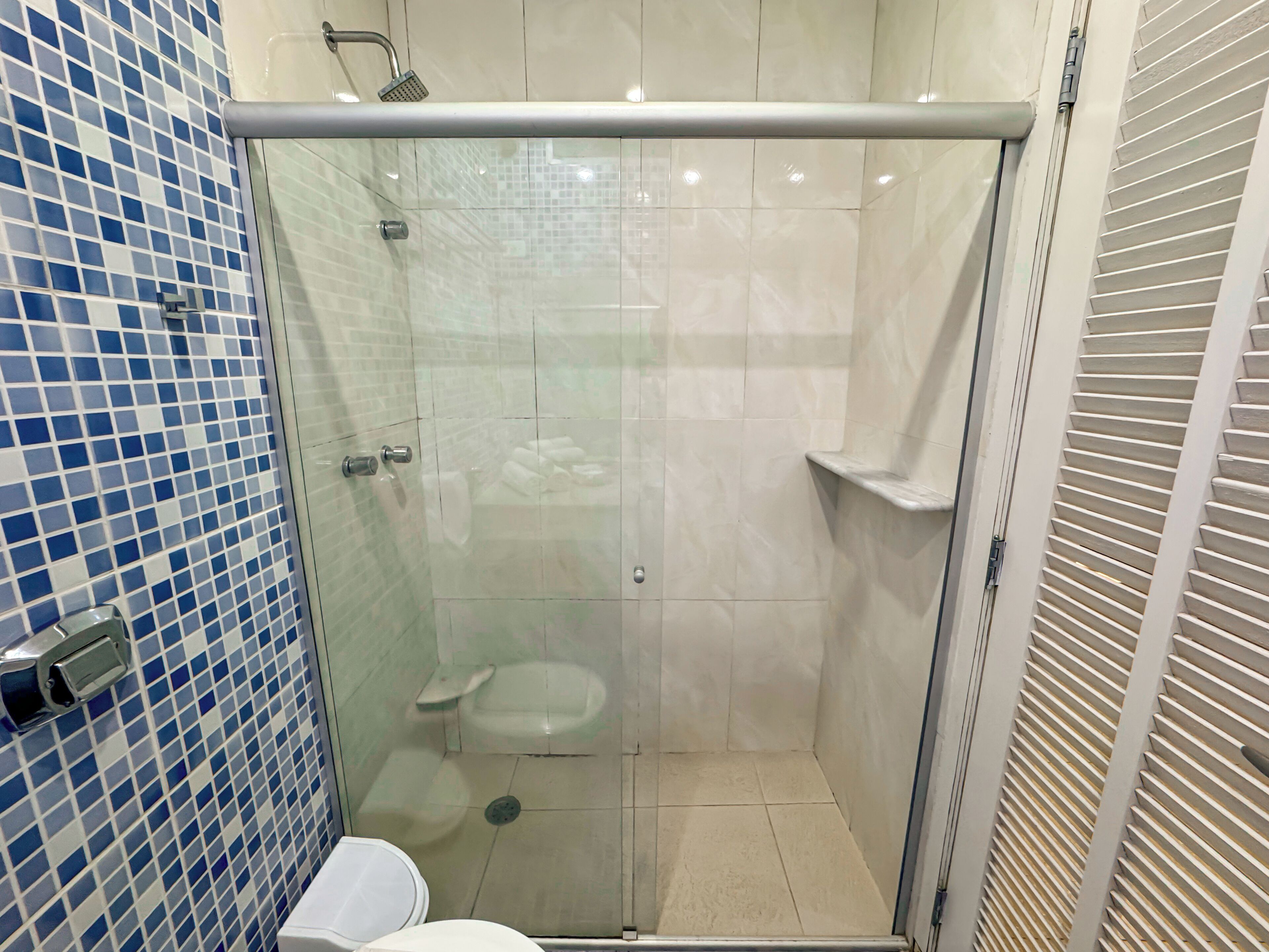 A glass-enclosed shower stall with a toilet and a sink.