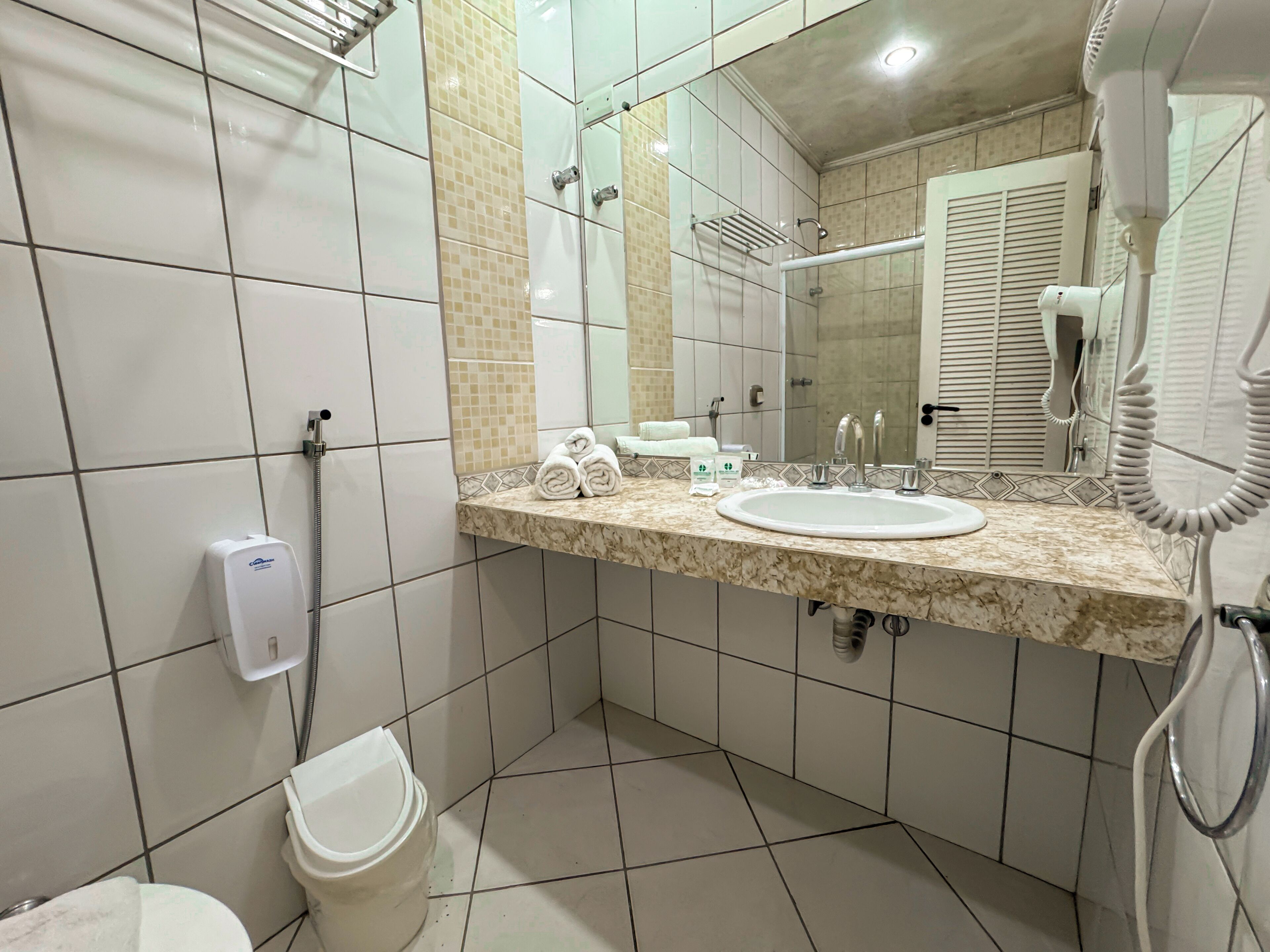 A bathroom with a sink, mirror, towel rack, and a handheld showerhead.