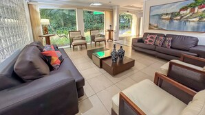 A modern living room with a sofa, armchairs, a coffee table, and a painting on the wall. - Hotel Nacional Inn Guarujá (Guarujá)