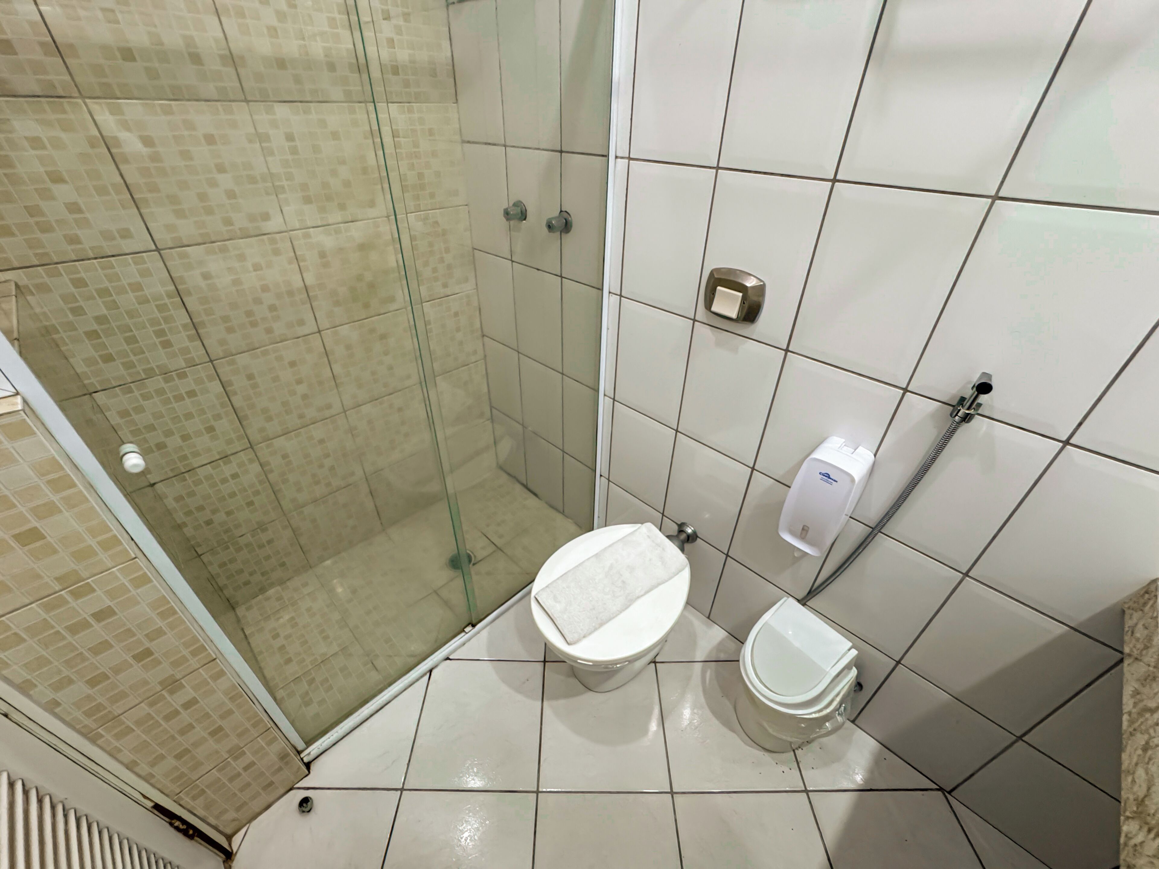 Ein Badezimmer mit Duschkabine, Toilette und Handtrockner.