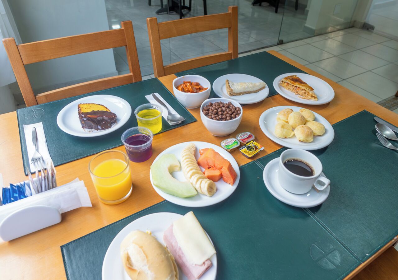 A breakfast table with plates of food, a cup of coffee, and a glass of orange juice.